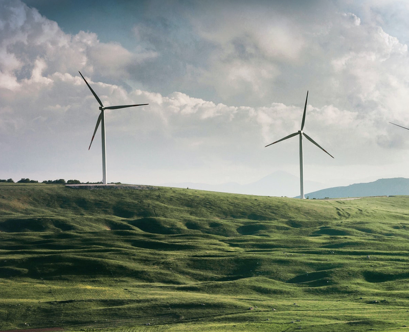 Wind turbines on a grass hill.